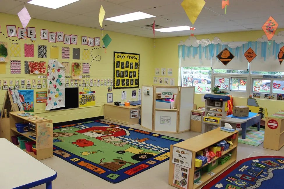 A colorful classroom with a large rug, shelves, and decorations