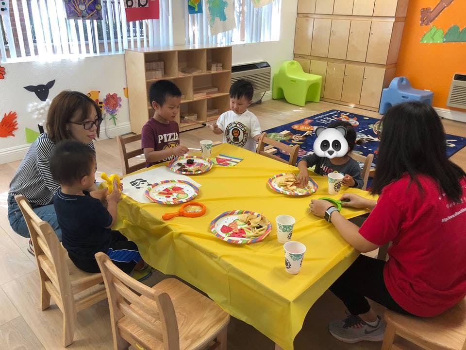 Adults and children sitting at a table with plates and cups