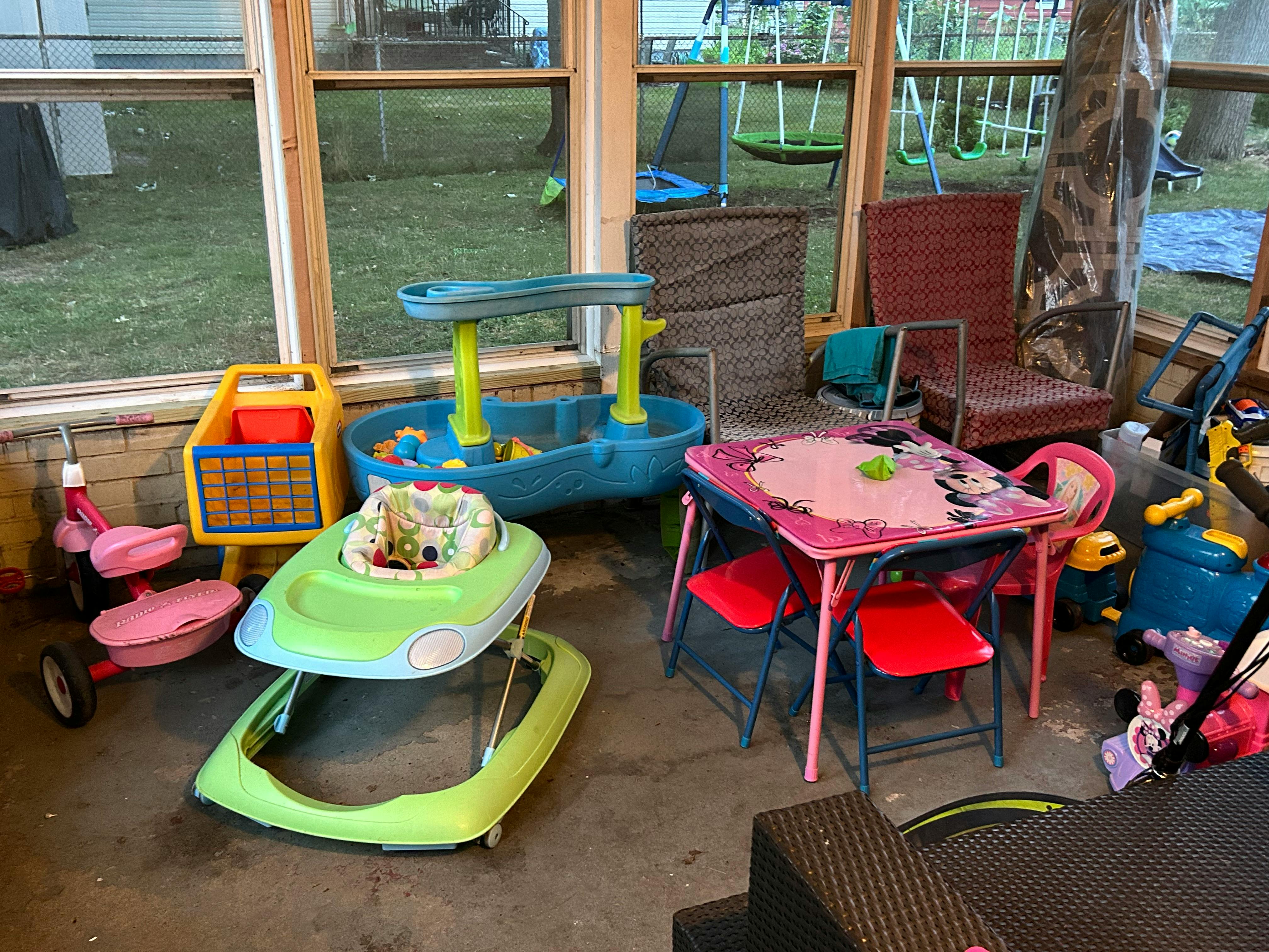 Children's toys including a walker, tricycle, sand and water table, and small table with chairs