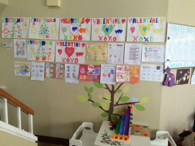 Wall with children's drawings and a tree decal above a small table