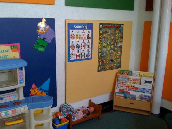 Playroom with toy kitchen, posters, book display, and doll in a bed