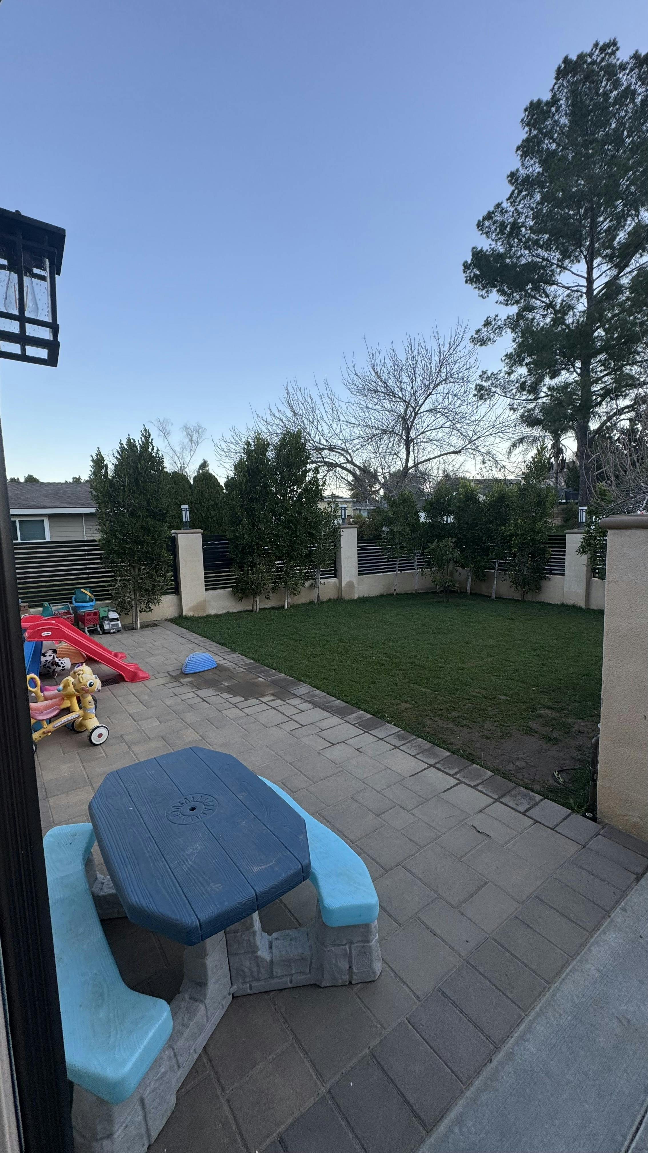 Children's picnic table and toys on a patio next to a grassy yard