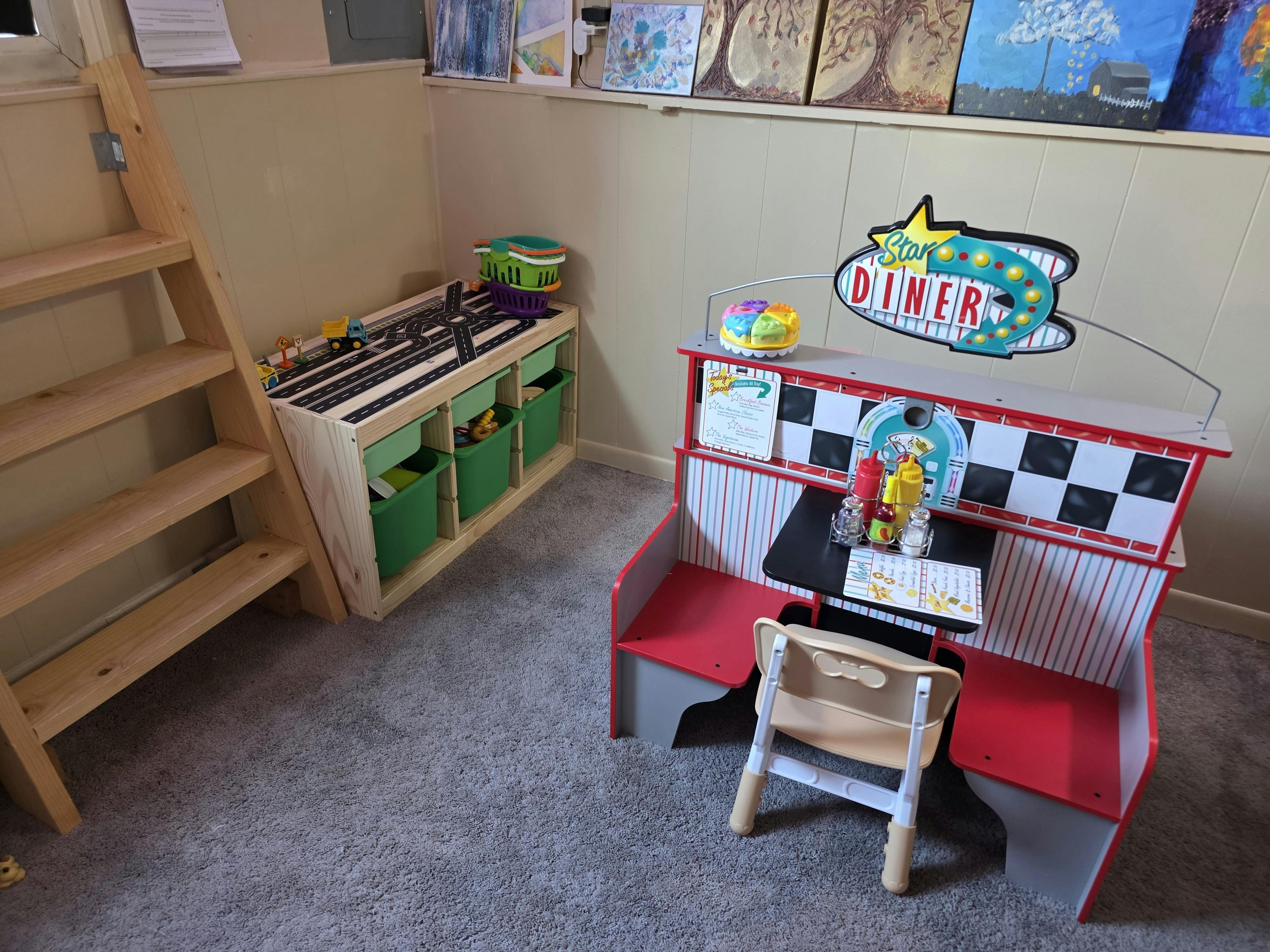 Playroom with a toy Star Diner set, a wooden shelf with storage, and a ladder