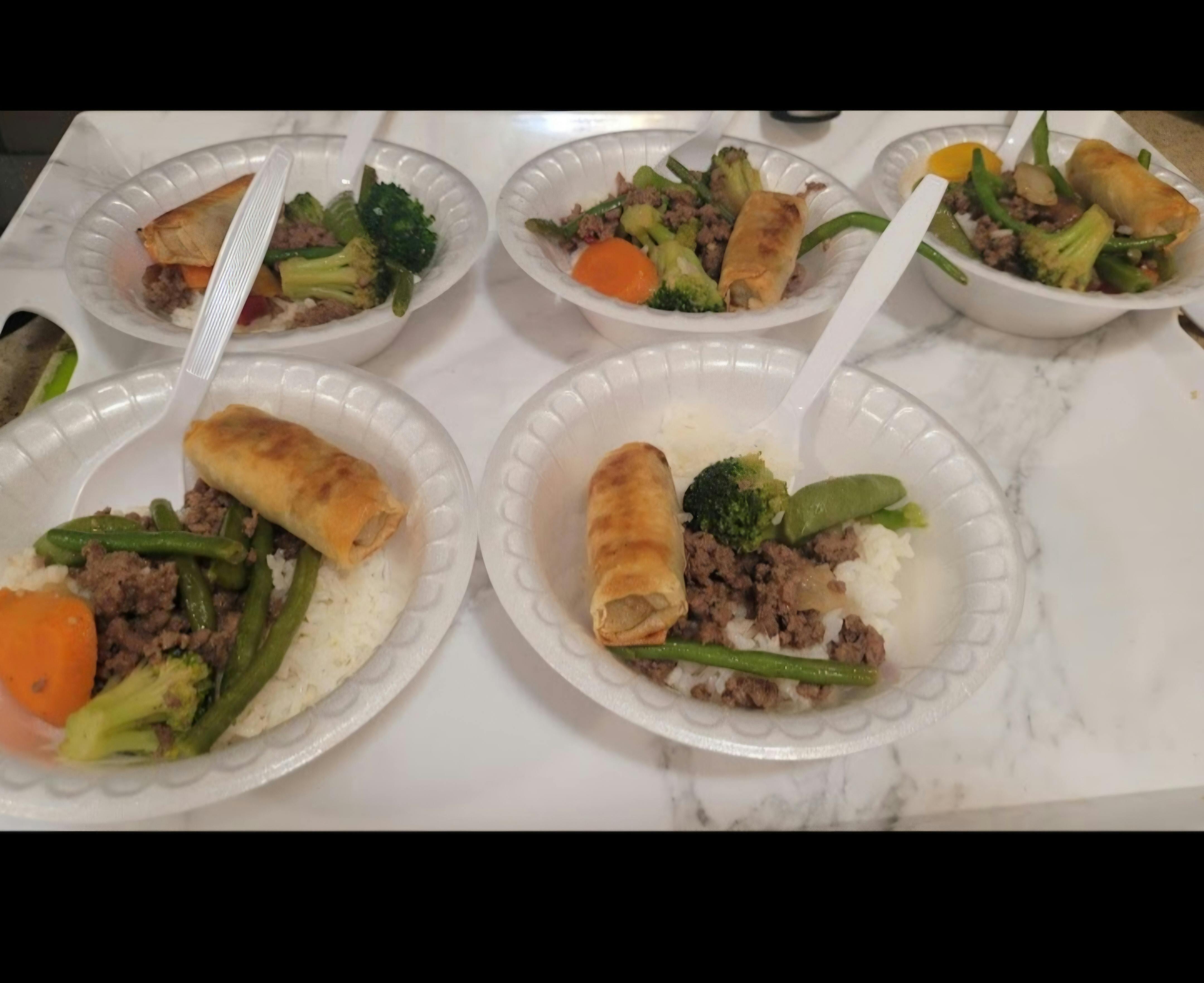Several disposable bowls with rice, ground meat, vegetables, and an egg roll