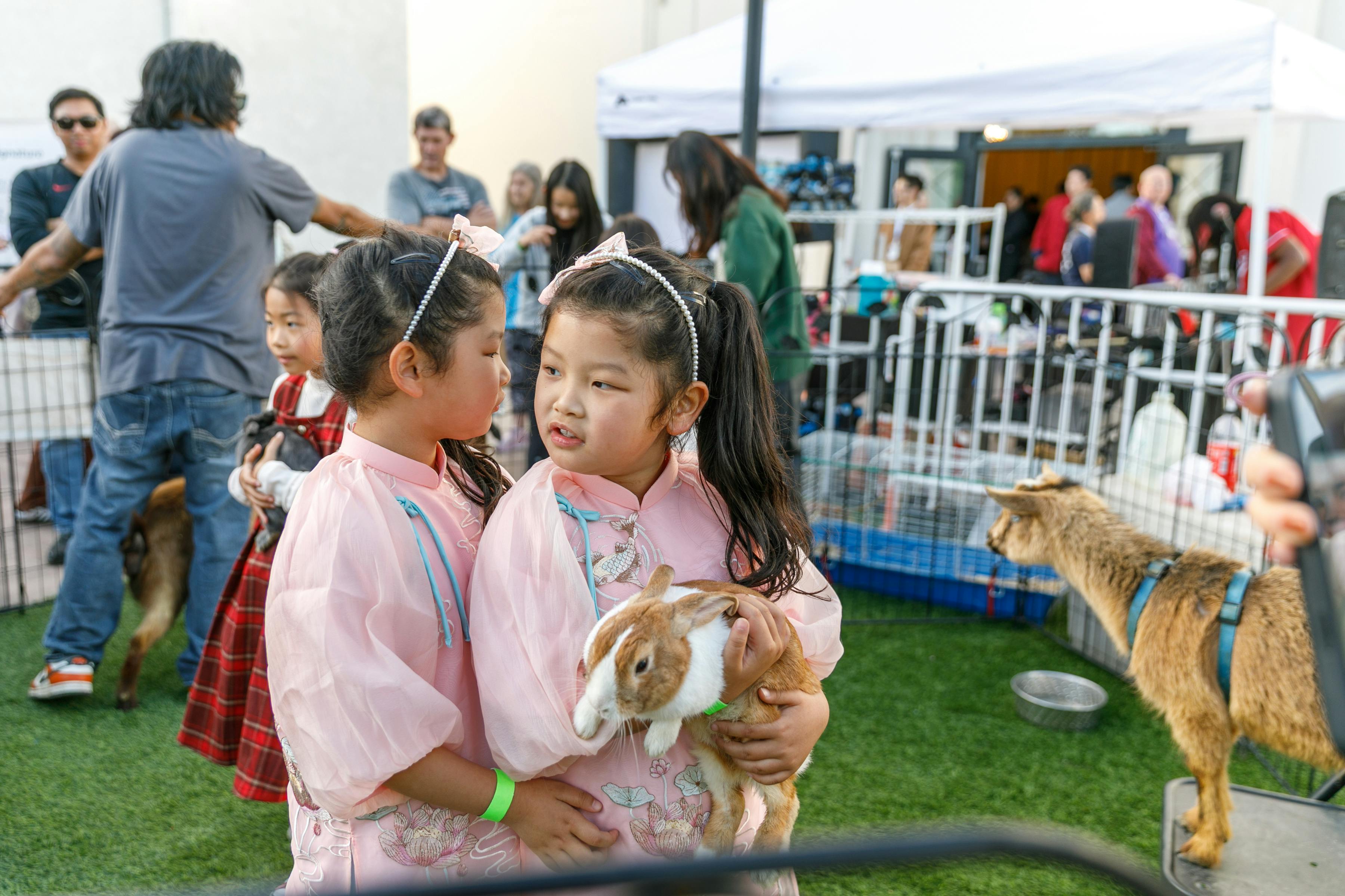 Two children holding a rabbit and conversing