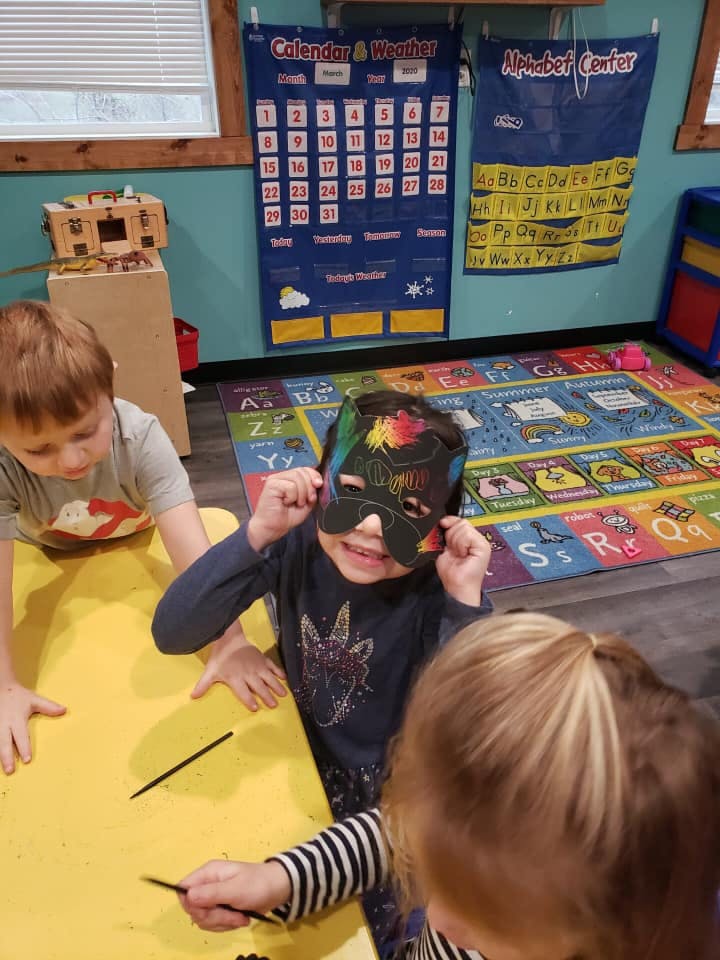 Child wearing a mask at a table with other children