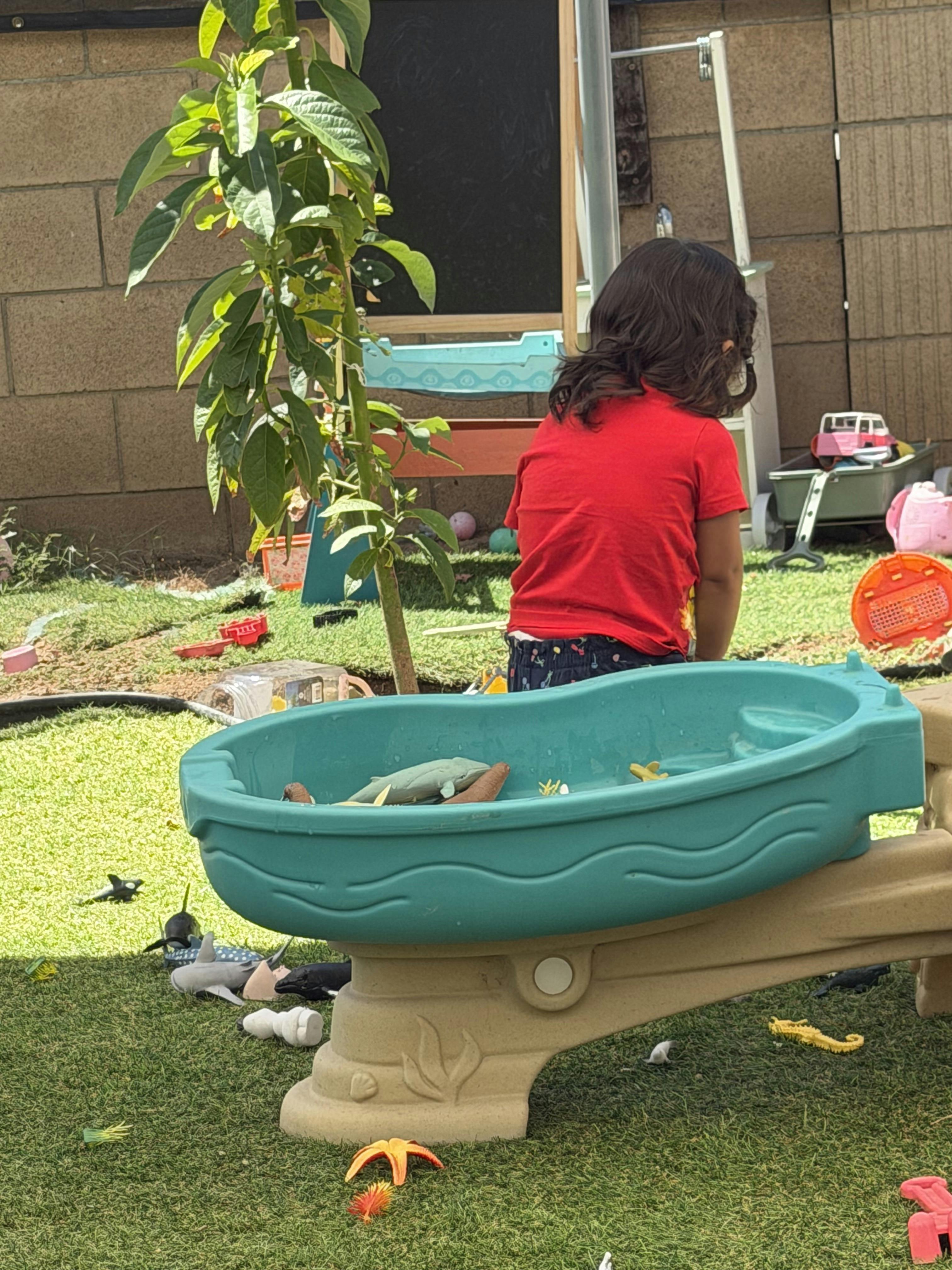 Child playing at a water table in a backyard