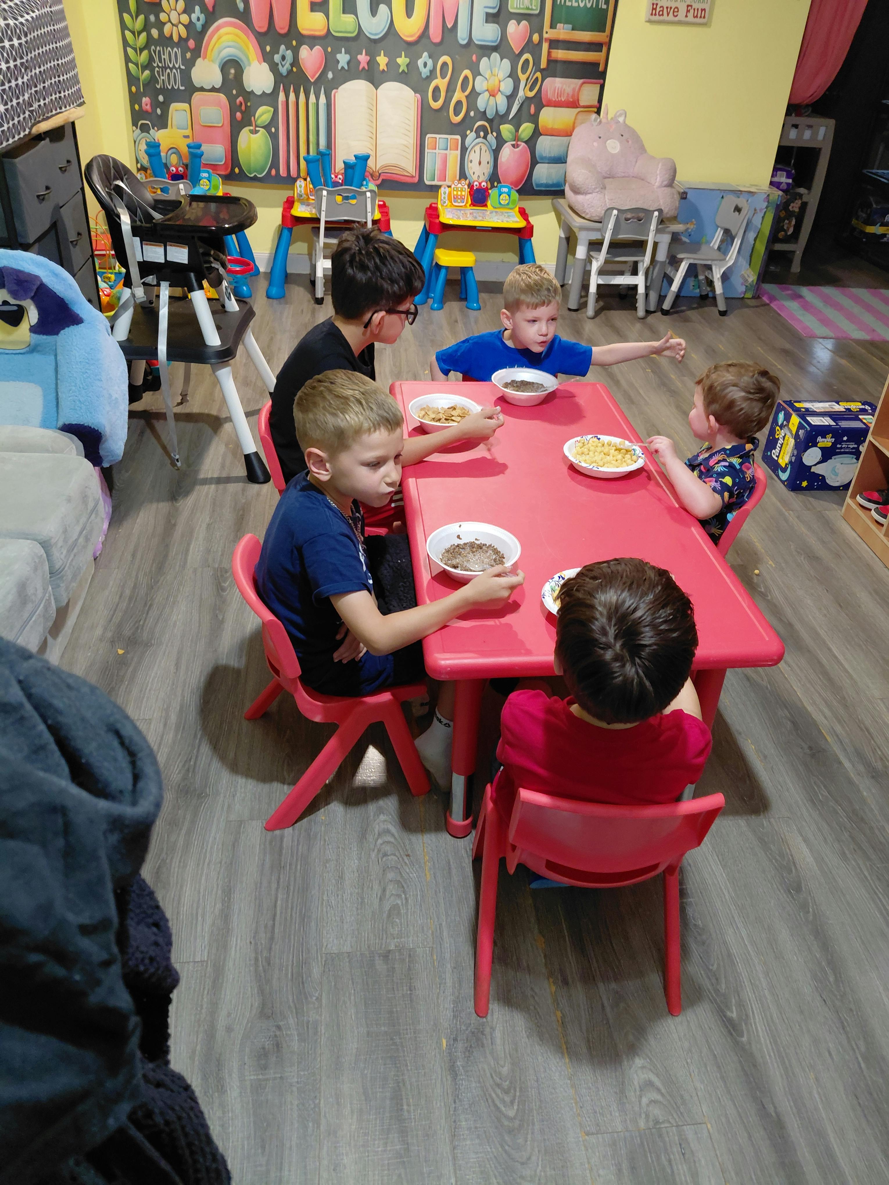 Children eating at a small red table in a classroom