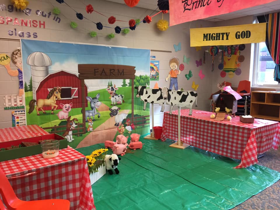 Classroom decorated with a farm backdrop, red and white checkered tables, and stuffed animals
