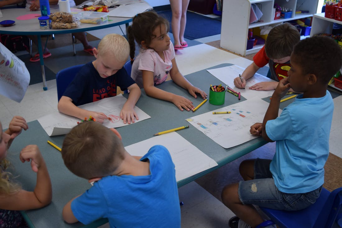 Children drawing at a table in a classroom