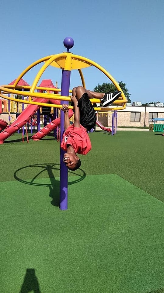 Child hanging upside down on playground equipment