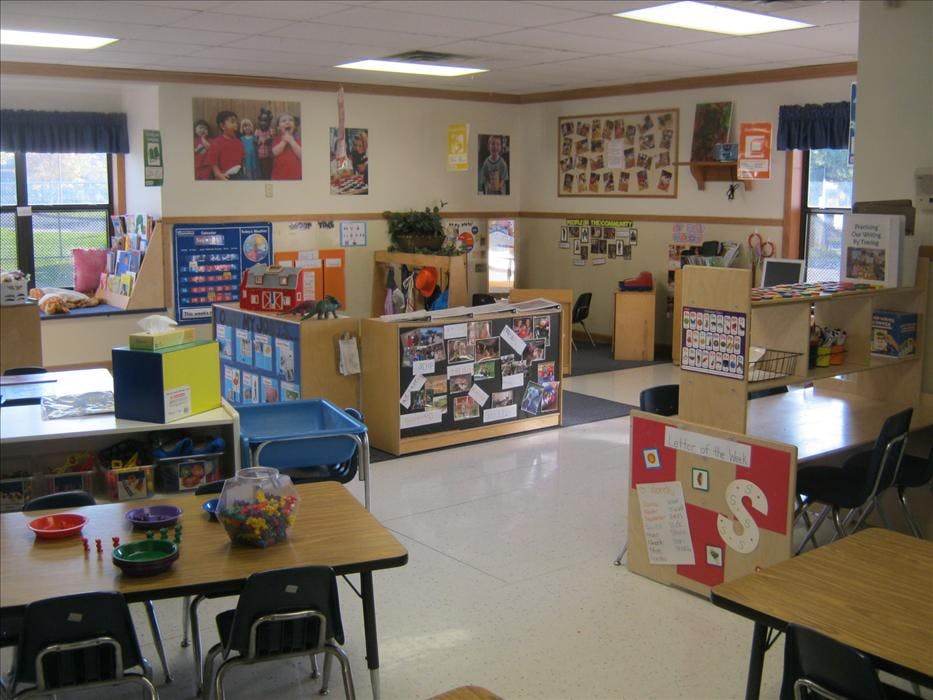 An empty classroom with small tables and chairs, and learning materials on display