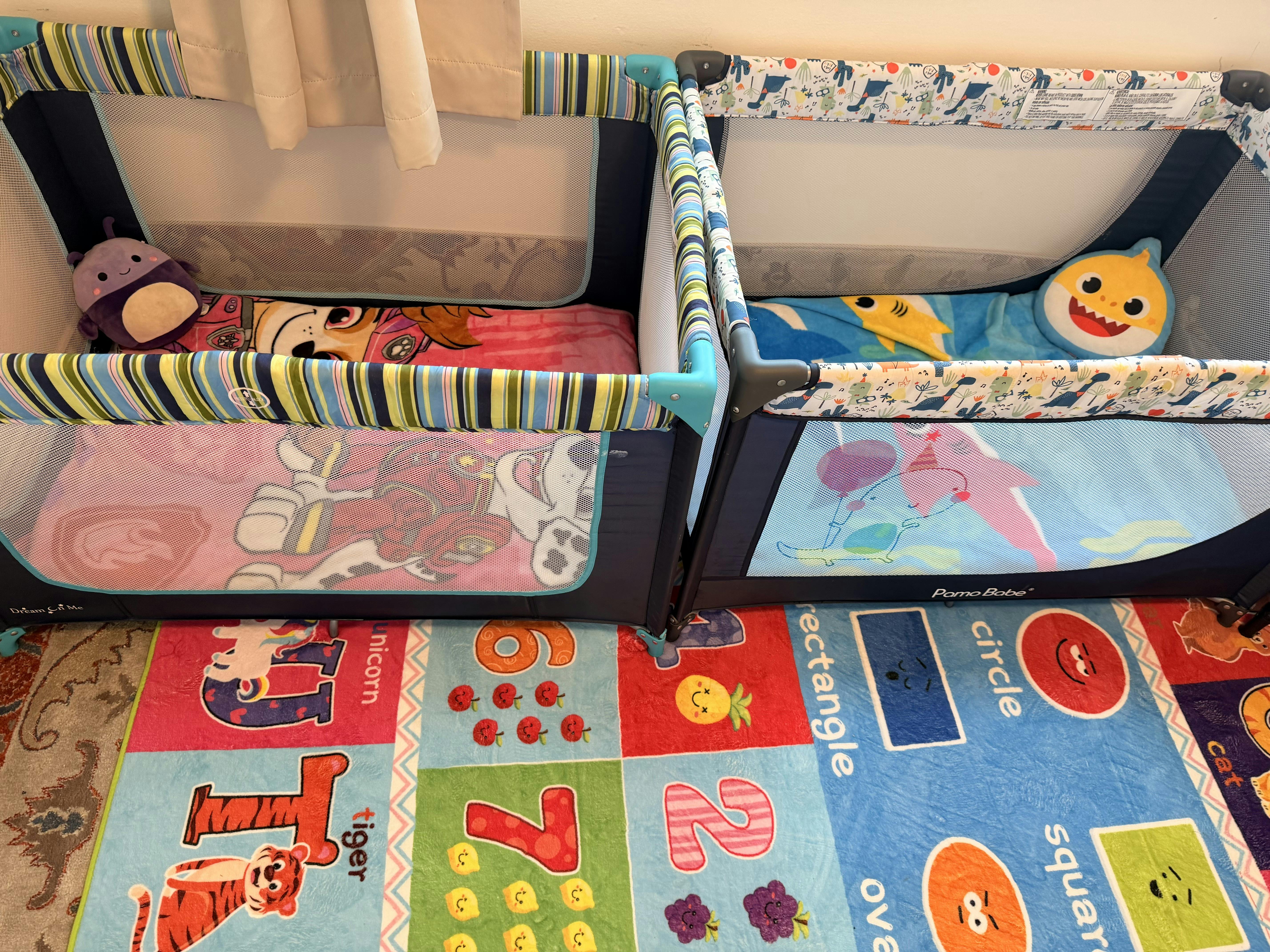 Two playpens side by side on a colorful educational floor mat