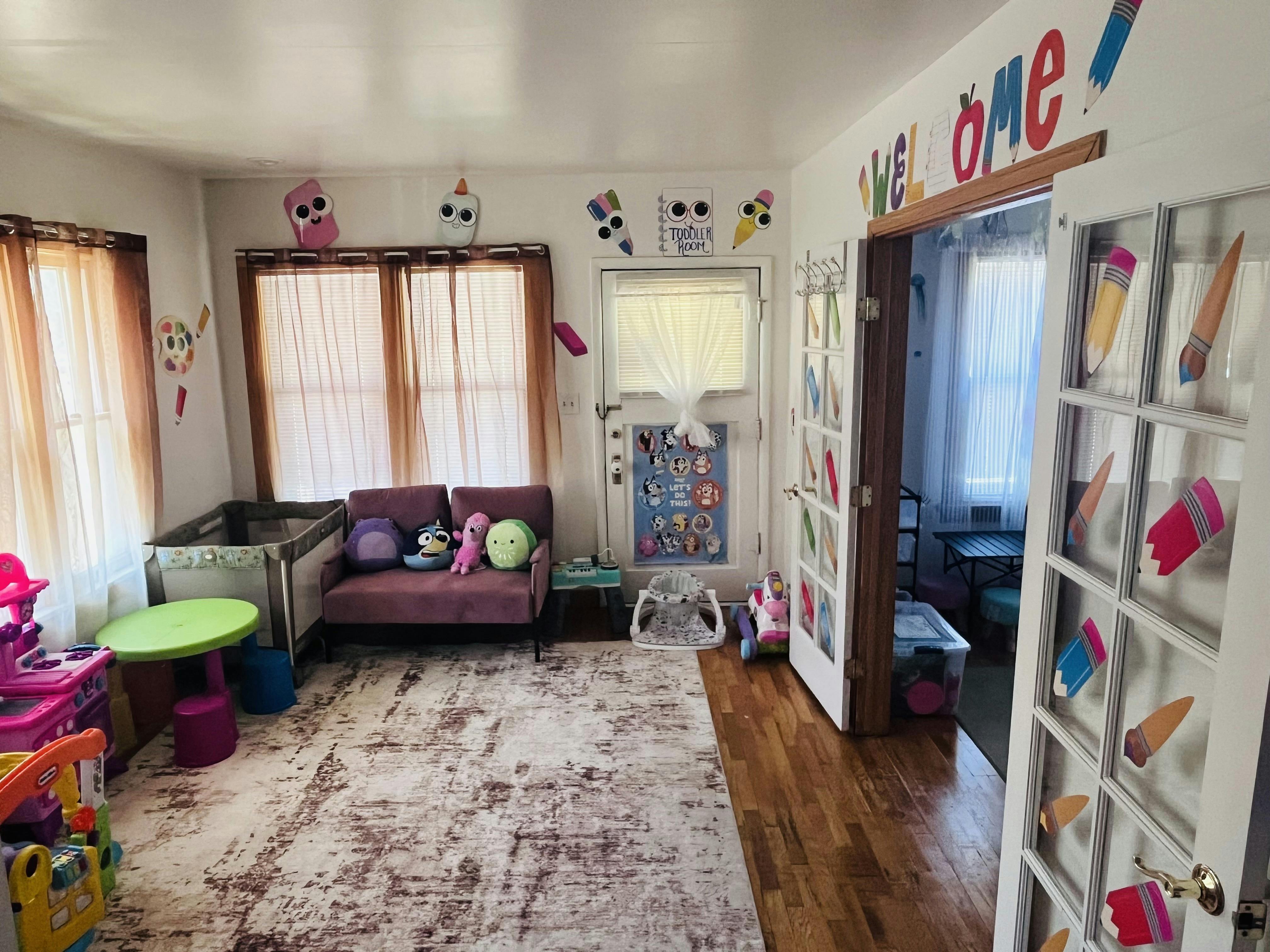 Childcare room with toys, a couch, and Welcome sign