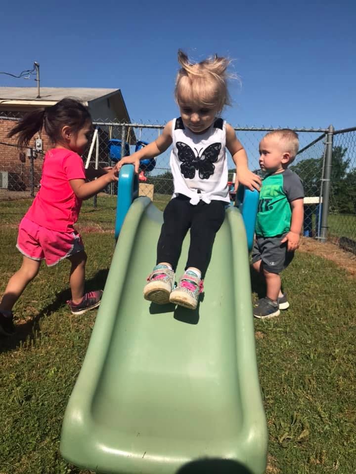 Three children playing on a slide outdoors