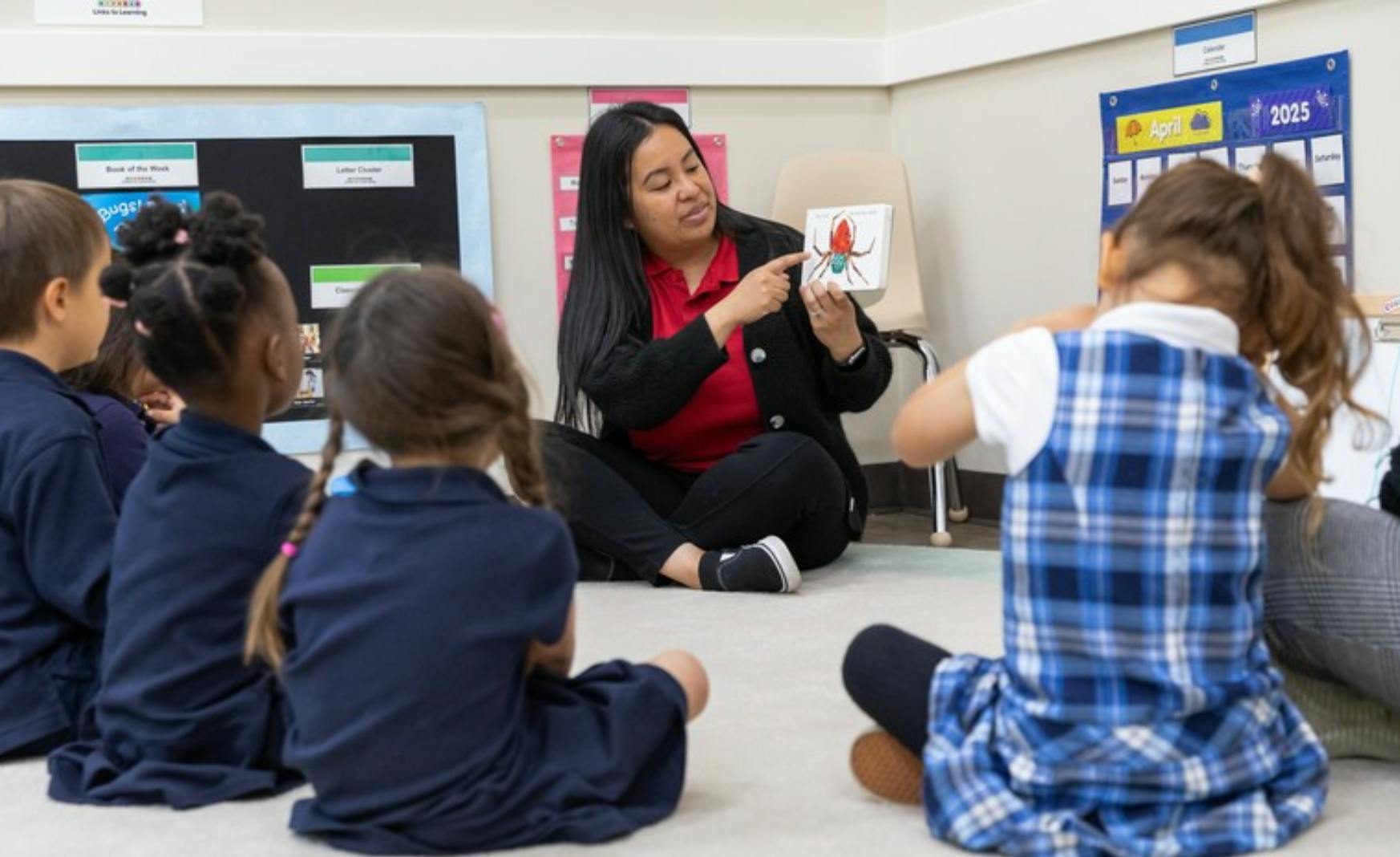 Person holding up a picture of an insect to children in a classroom
