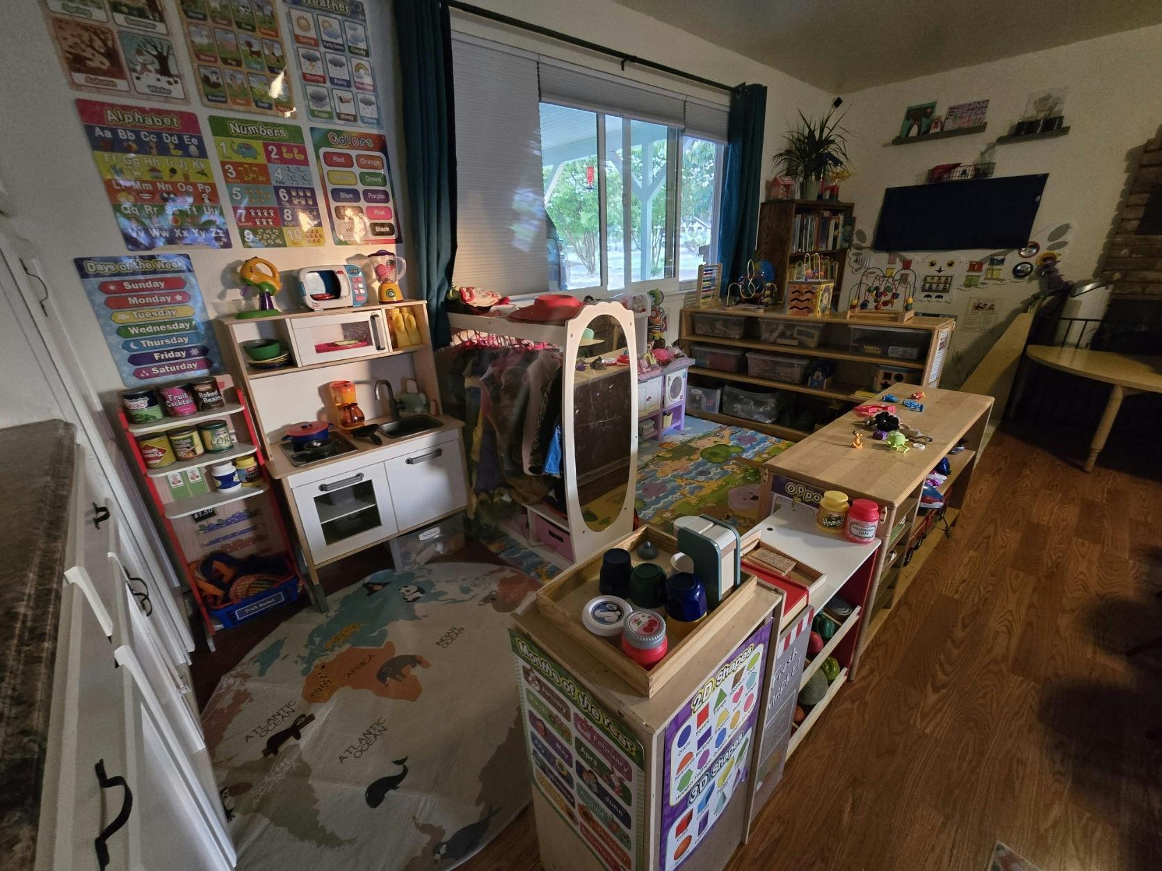 Playroom with various toys, shelves, and a small kitchen set of kitchen set