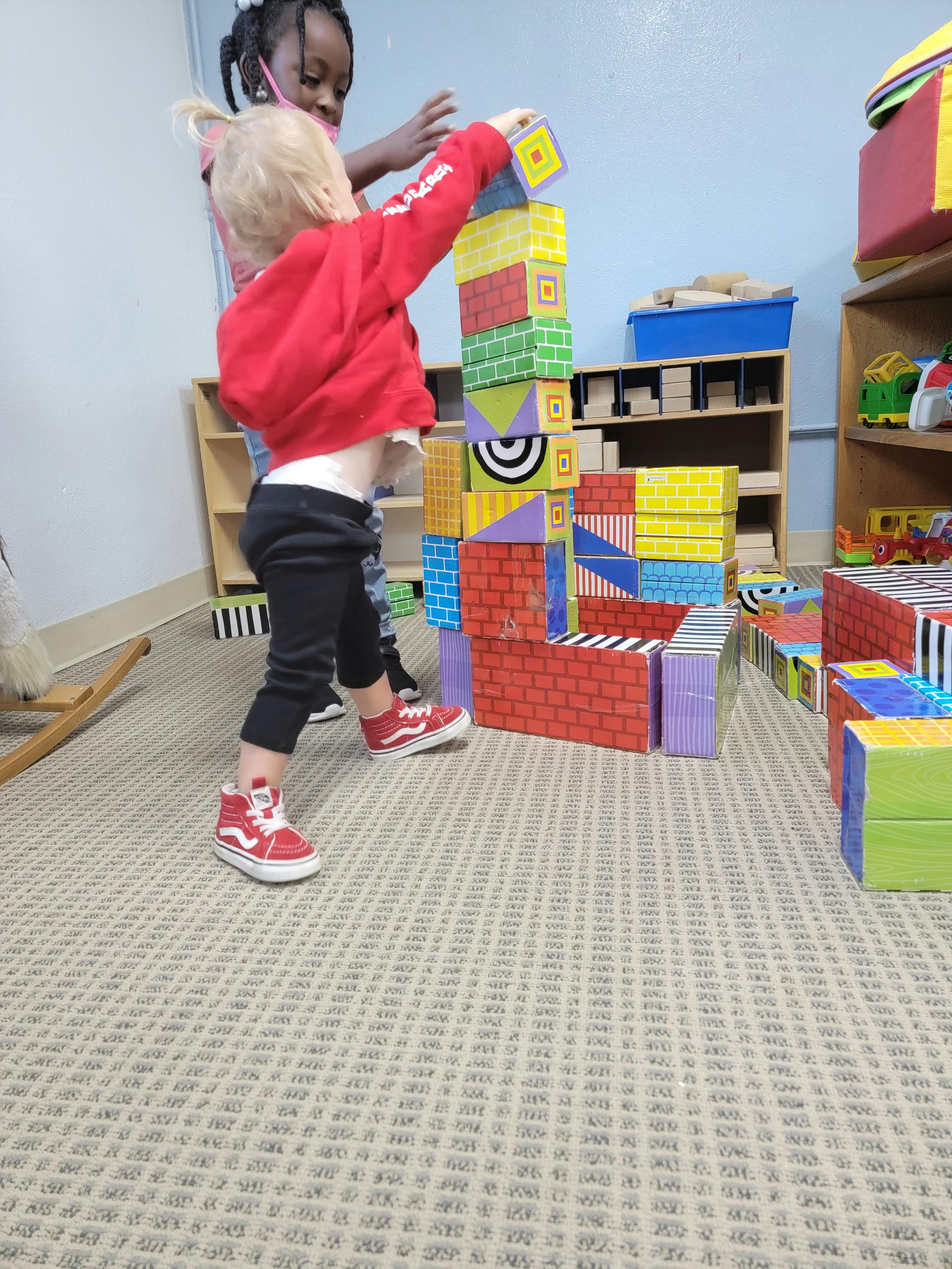 Two children playing with large colorful building blocks