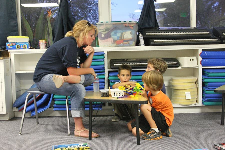 Adult and three children at a small table in a classroom