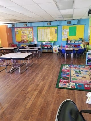 Classroom with small tables and chairs, bulletin boards on the wall
