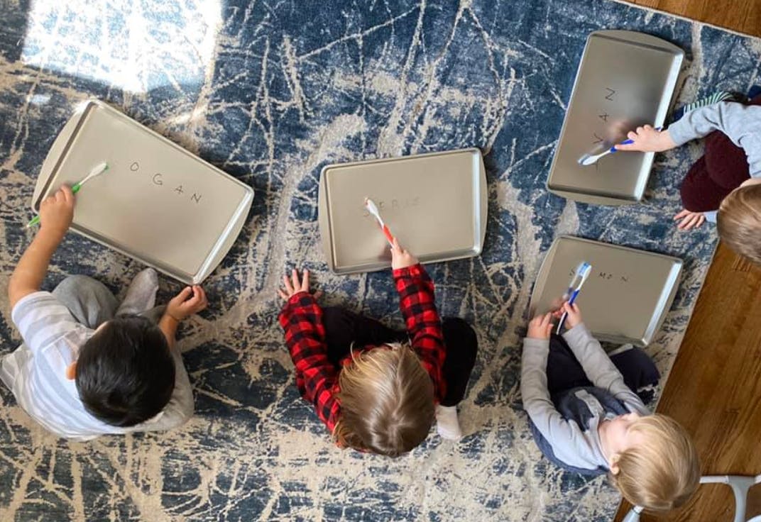 Children drawing on baking sheets with toothbrushes
