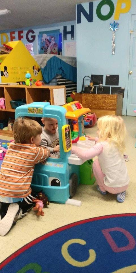 Three children playing with toys in a classroom