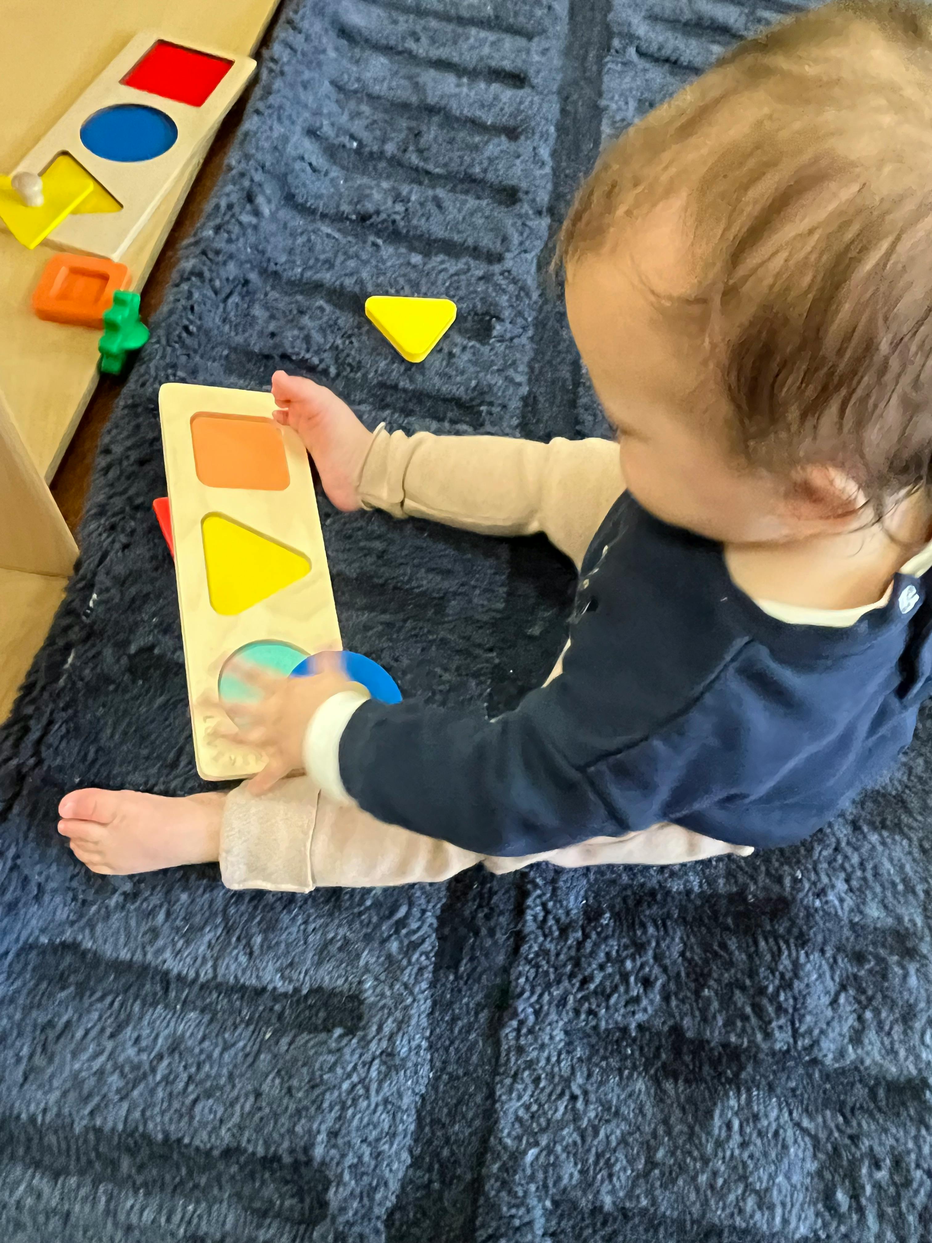Child playing with a wooden shape sorter toy