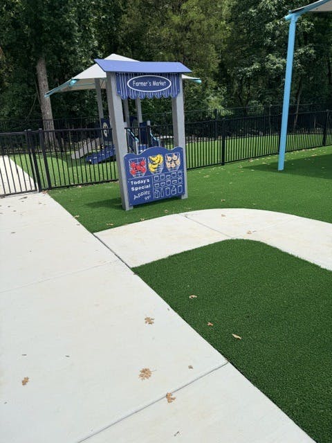 Playground structure labeled Farmer's Market on a grassy area