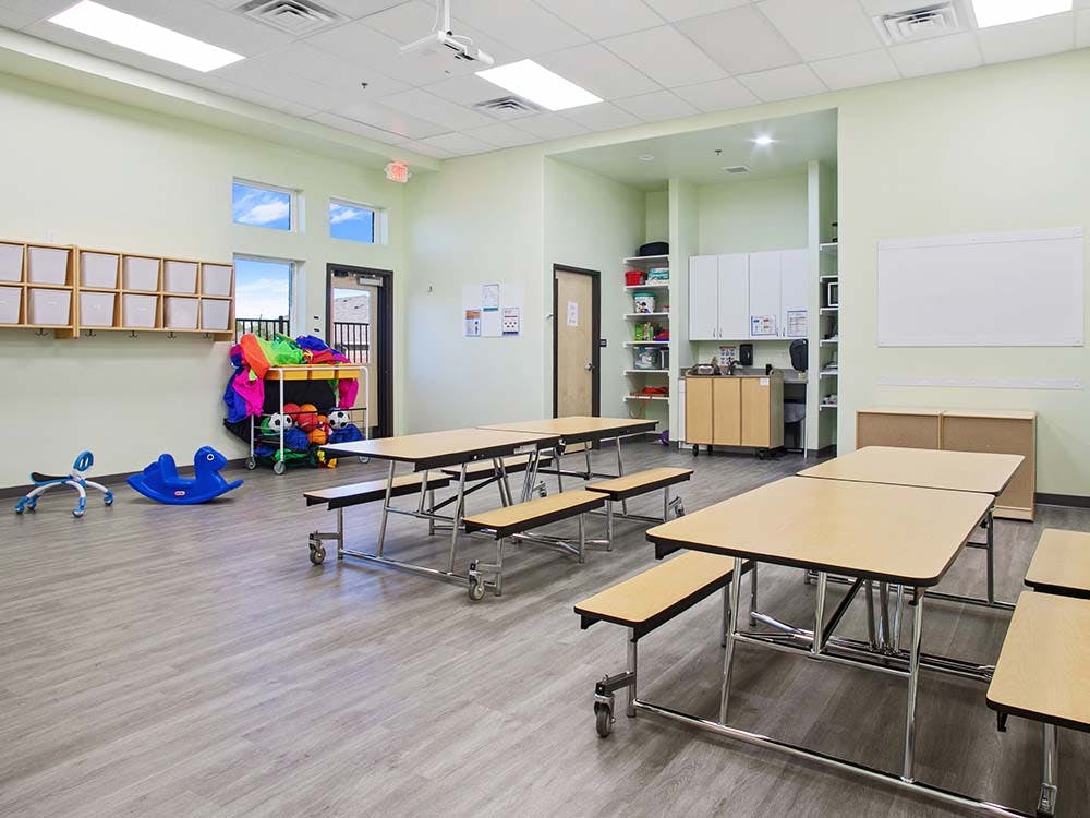 Classroom with tables, benches, cubbies, toys, and whiteboards