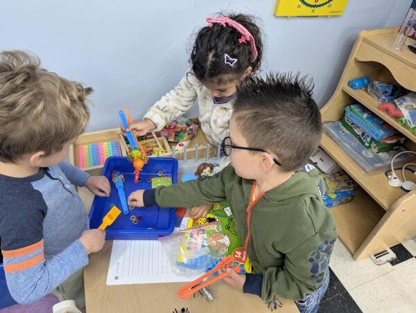 Three children playing with toys at a table