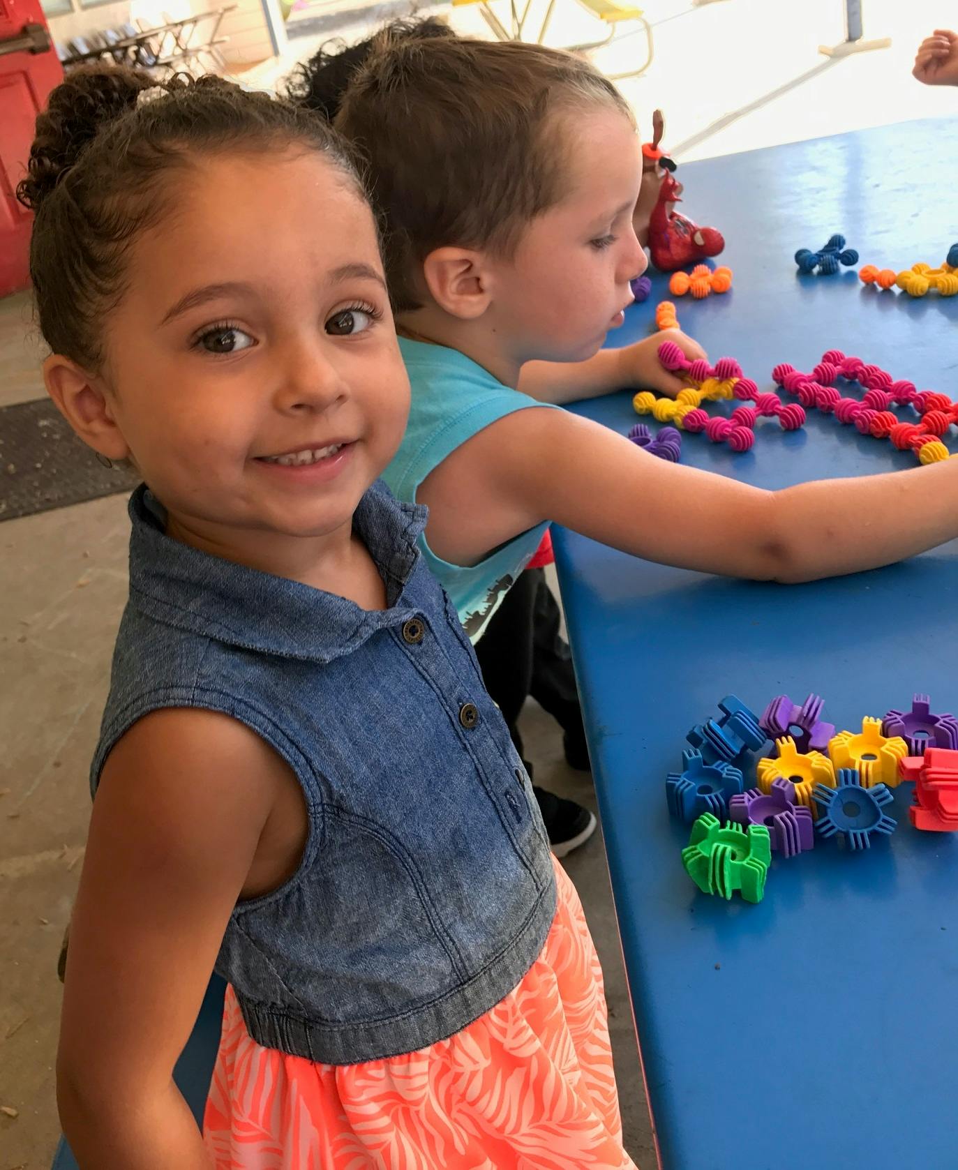 Two children playing with colorful interlocking toys at a table