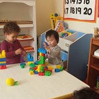 Two children playing with colorful building blocks at a table