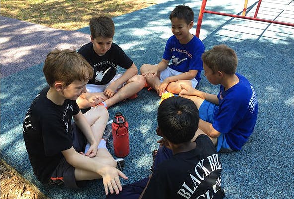 Five children sitting in a circle on the ground