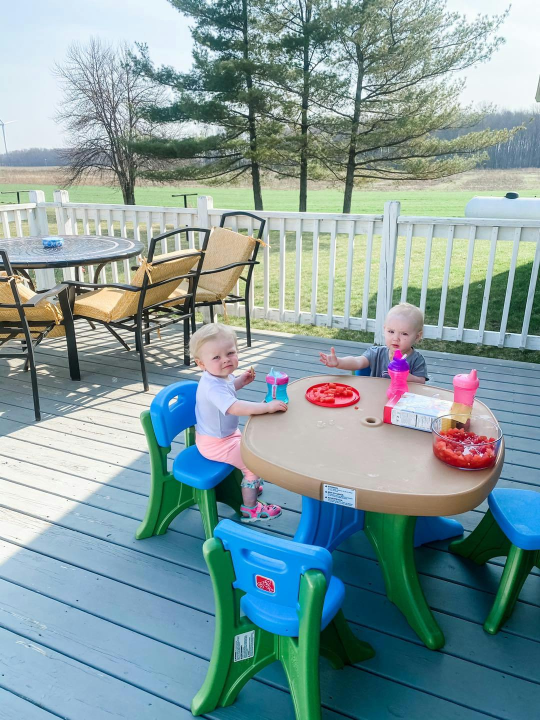 Two children sitting at a small table on a deck