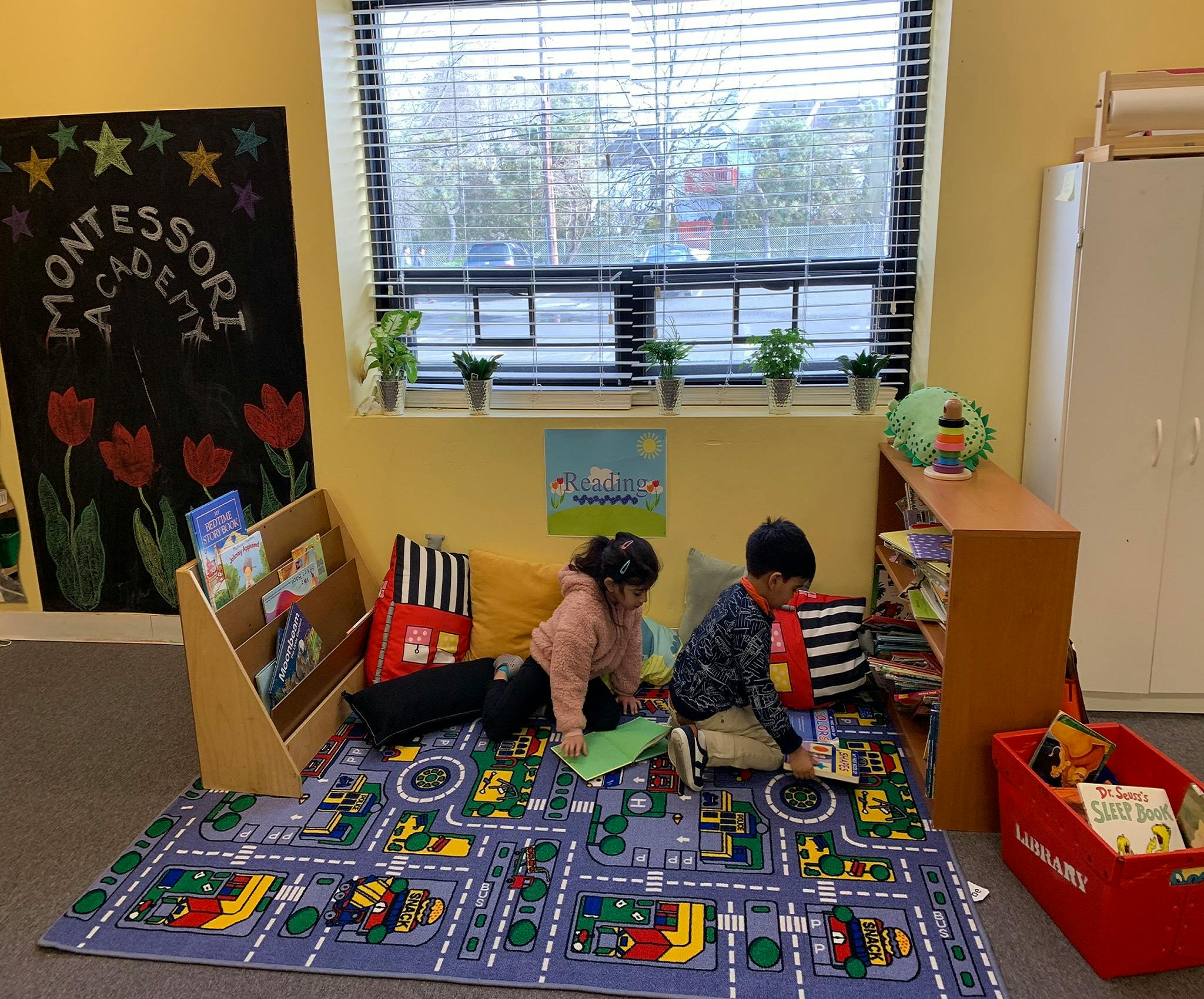Two children sitting on a rug and looking at books