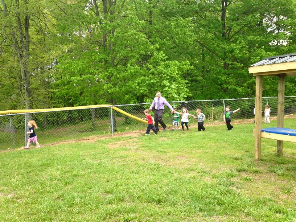 Adult and children walking on grass near a fence