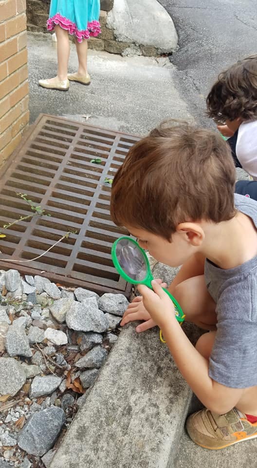 Child looking through a magnifying glass at the ground