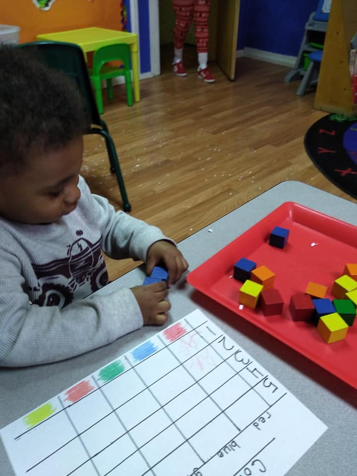 Child playing with colorful blocks and a chart at a table