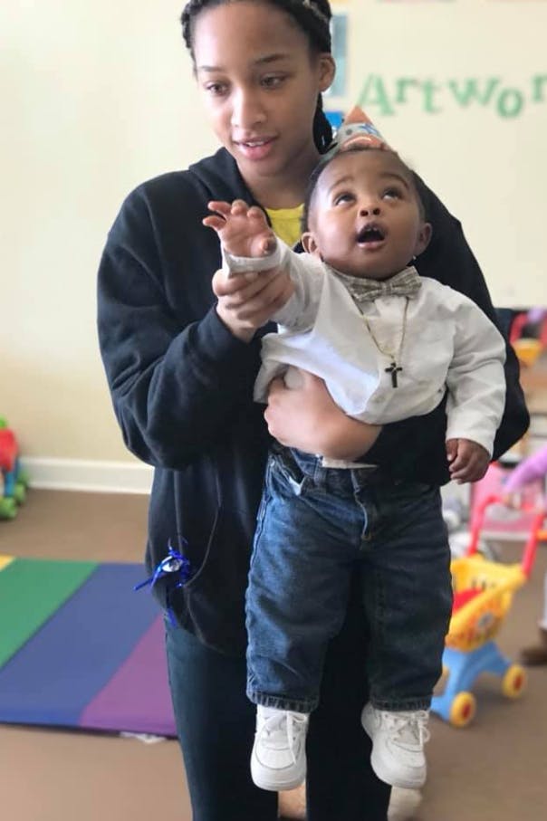 Person holding a child wearing a party hat