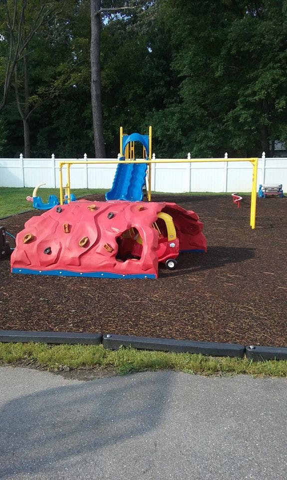 Playground with a red climbing structure, blue slide, and yellow swing set