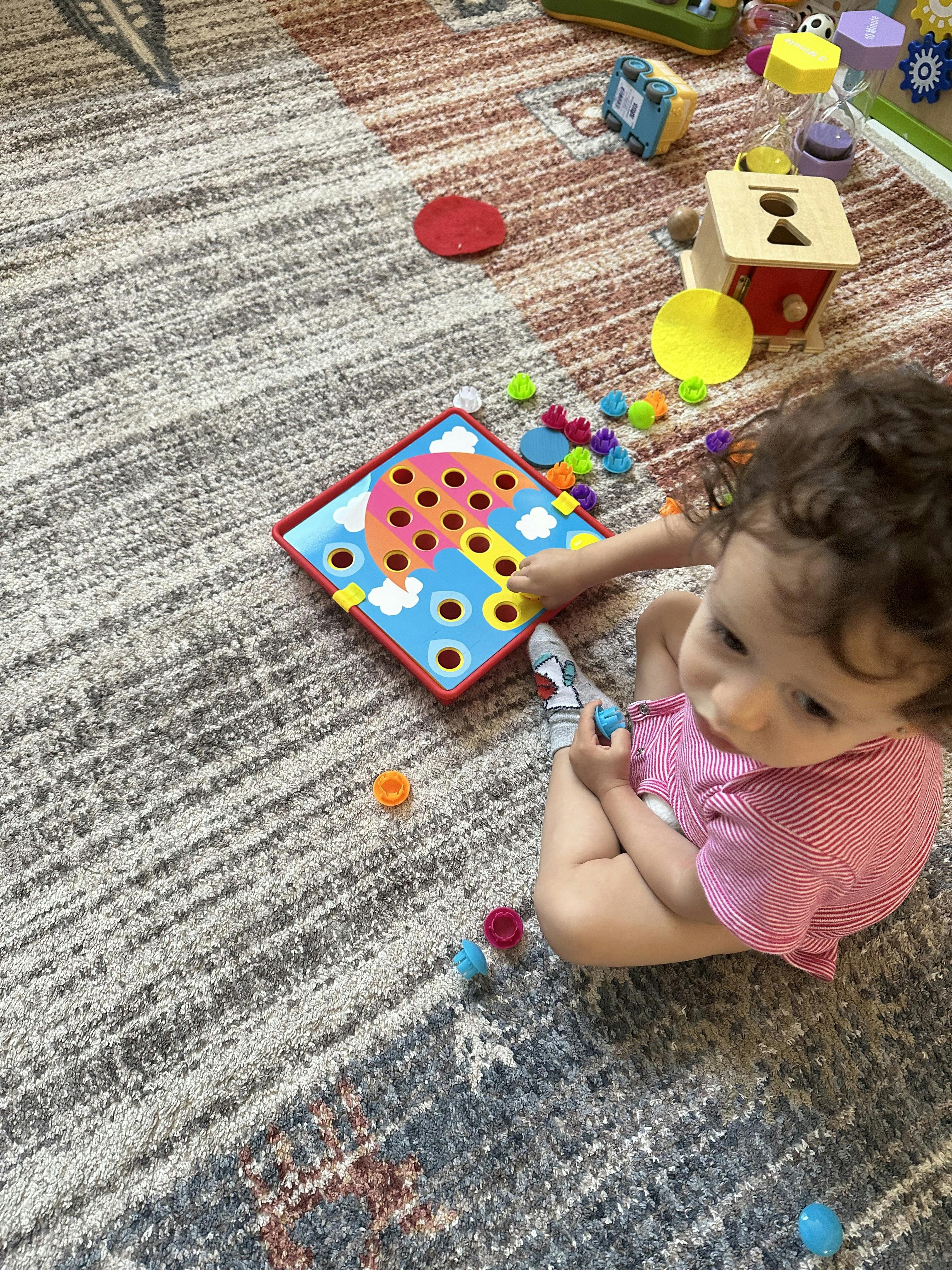 Child playing with a pegboard toy on a rug