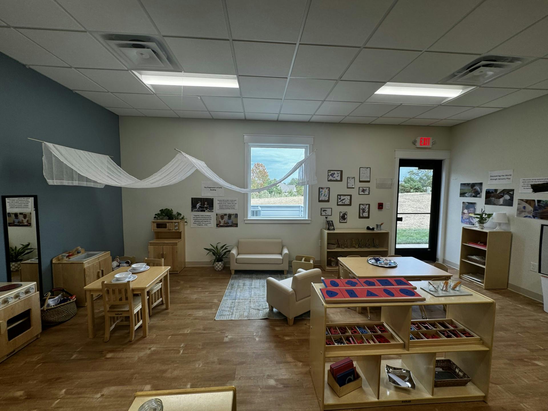 Classroom with small tables and chairs, shelves, and a window