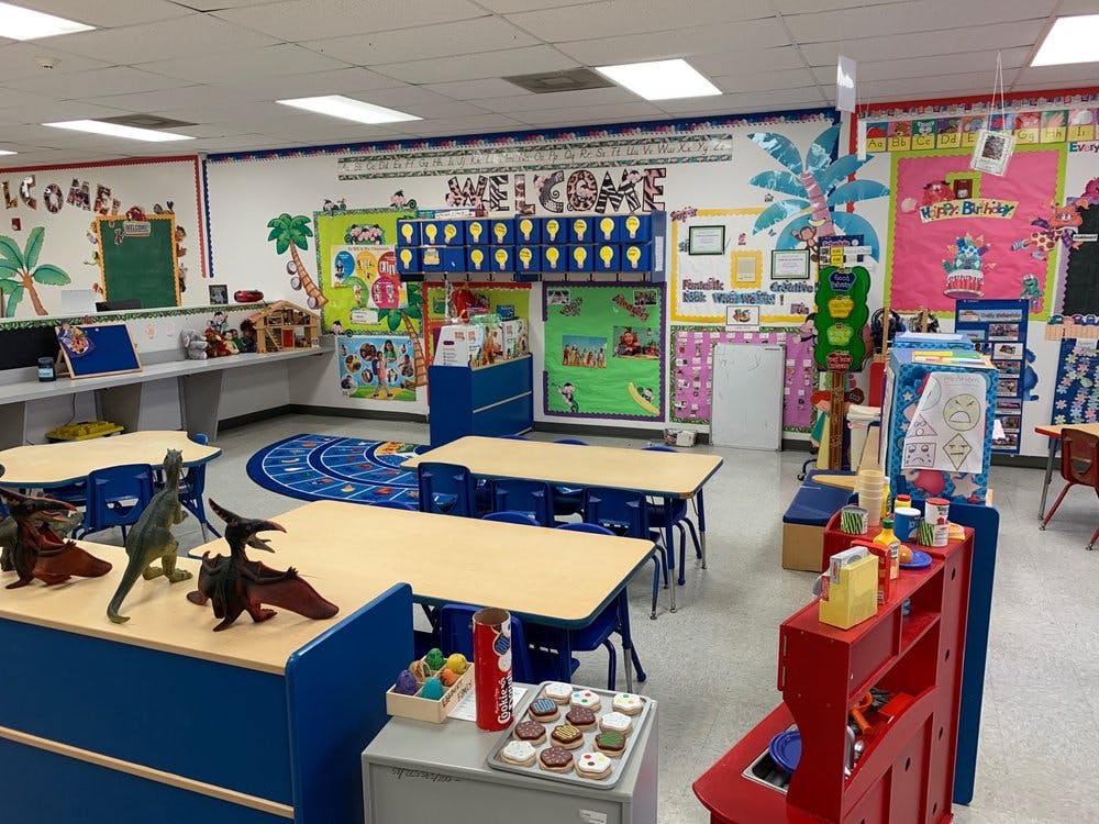 Classroom with small tables and chairs, decorated walls, and toys