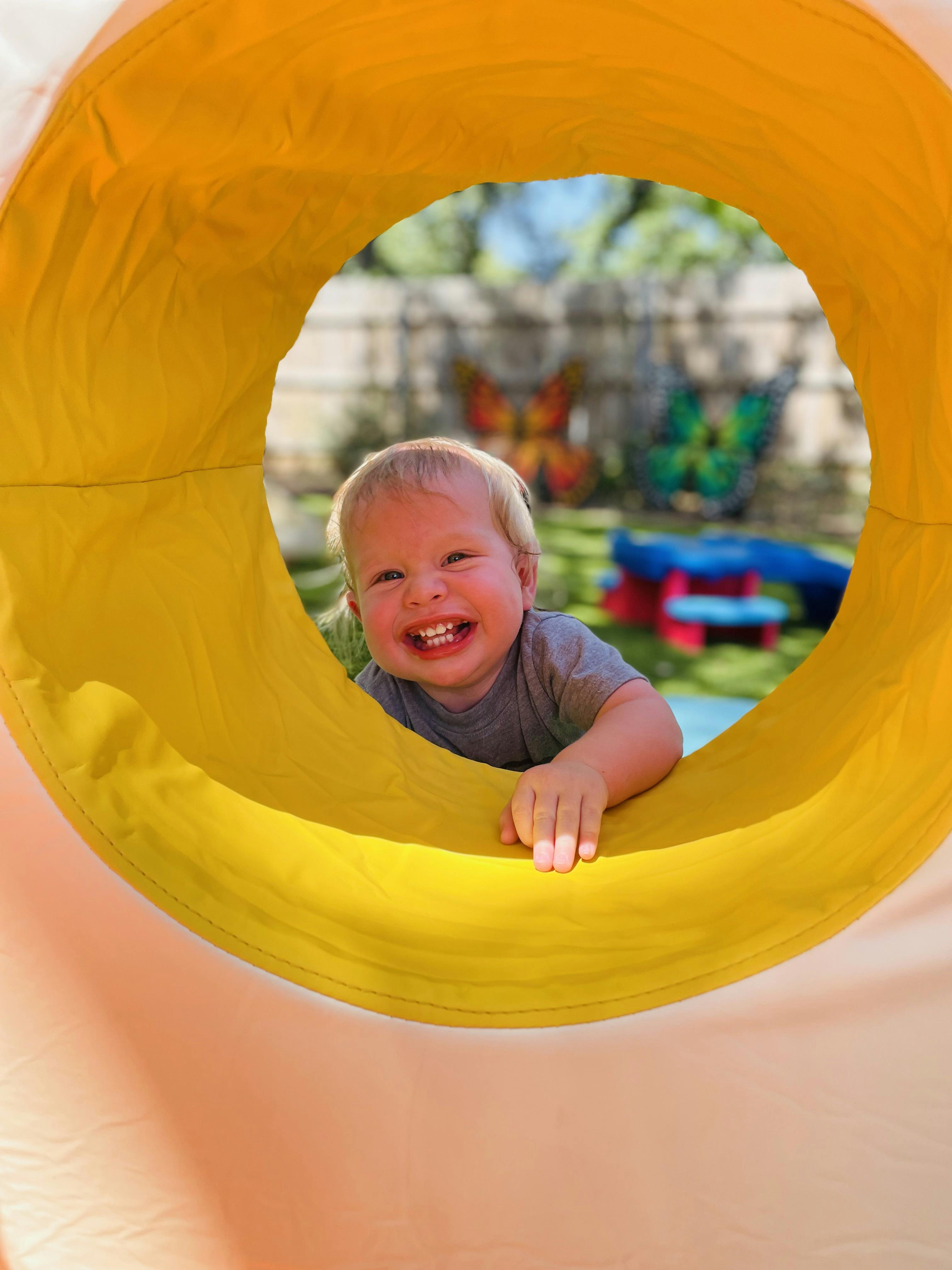 Child looking through a yellow tunnel