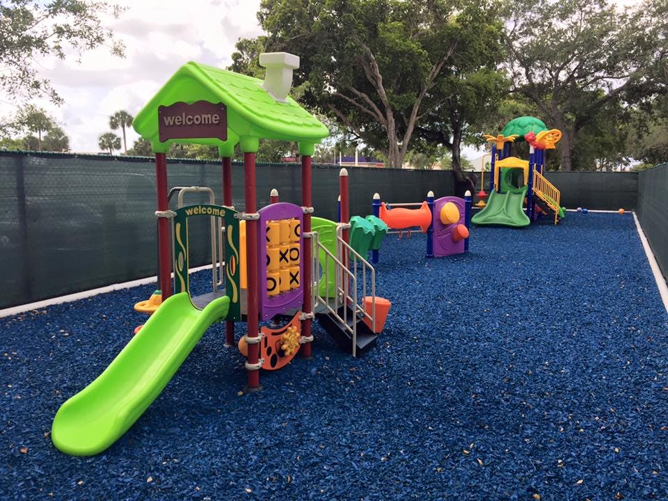 Playground with green and purple play structure, slide, and blue ground covering