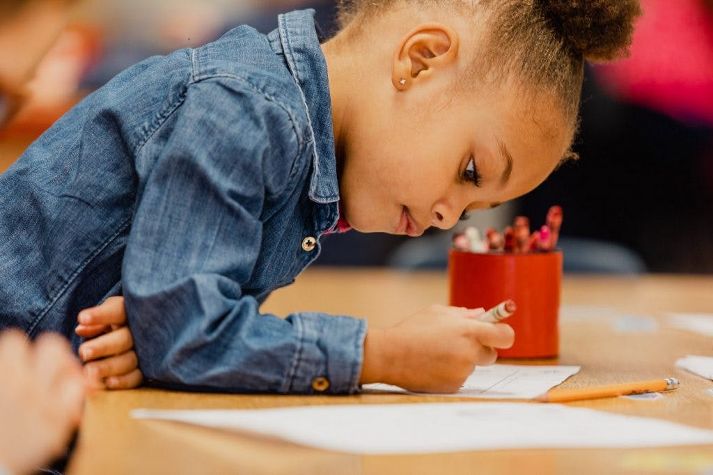 Child drawing on paper at a table