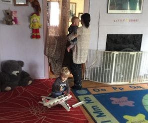 Person holding child, another child playing with toy airplane