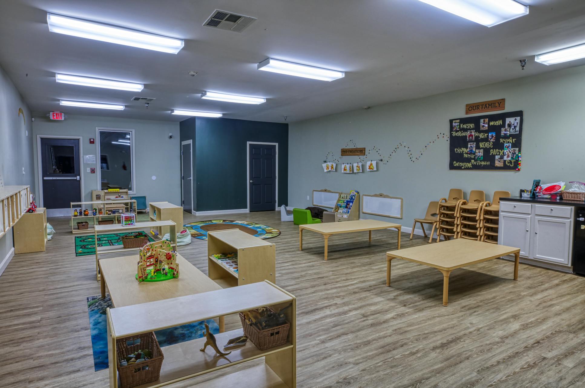 An empty classroom with small wooden tables and chairs