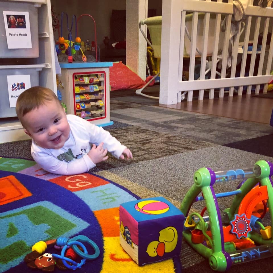 Child on a colorful rug with toys
