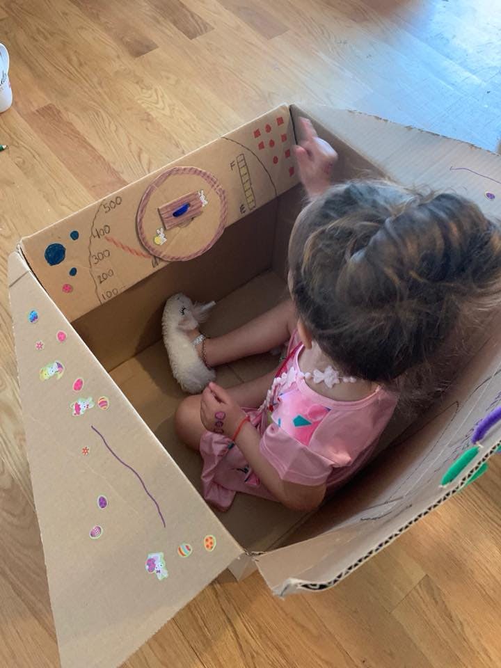 Child sitting in a decorated cardboard box